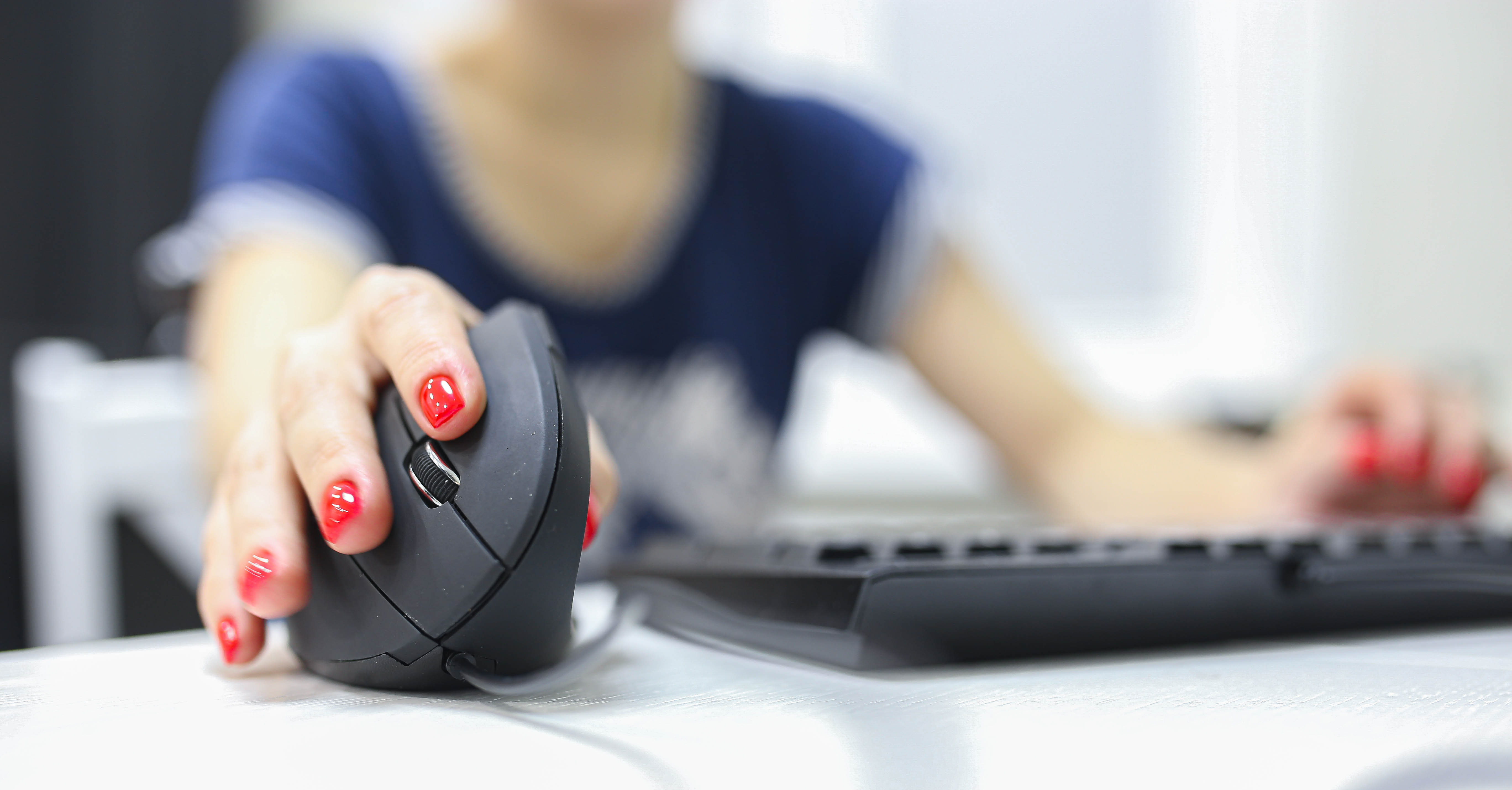 Die Hand einer Frau verwendet eine vertikal- ergonomische Computermaus.