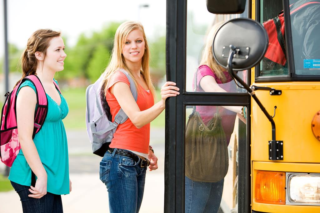 Girls looks to the side while boarding the school bus